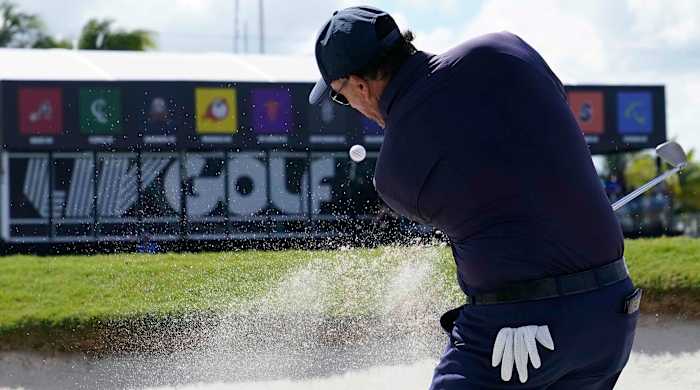 Phil Mickelson is shown hitting out of a bunker at the 2022 LIV Golf Invitational Miami Team Championship.